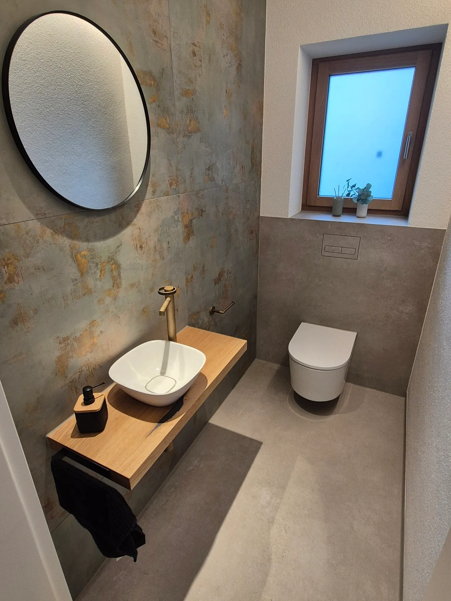 Gäste-WC mit großformatigen Wandplatten in Rost-Optik, grauer Boden und Holz-Waschtisch