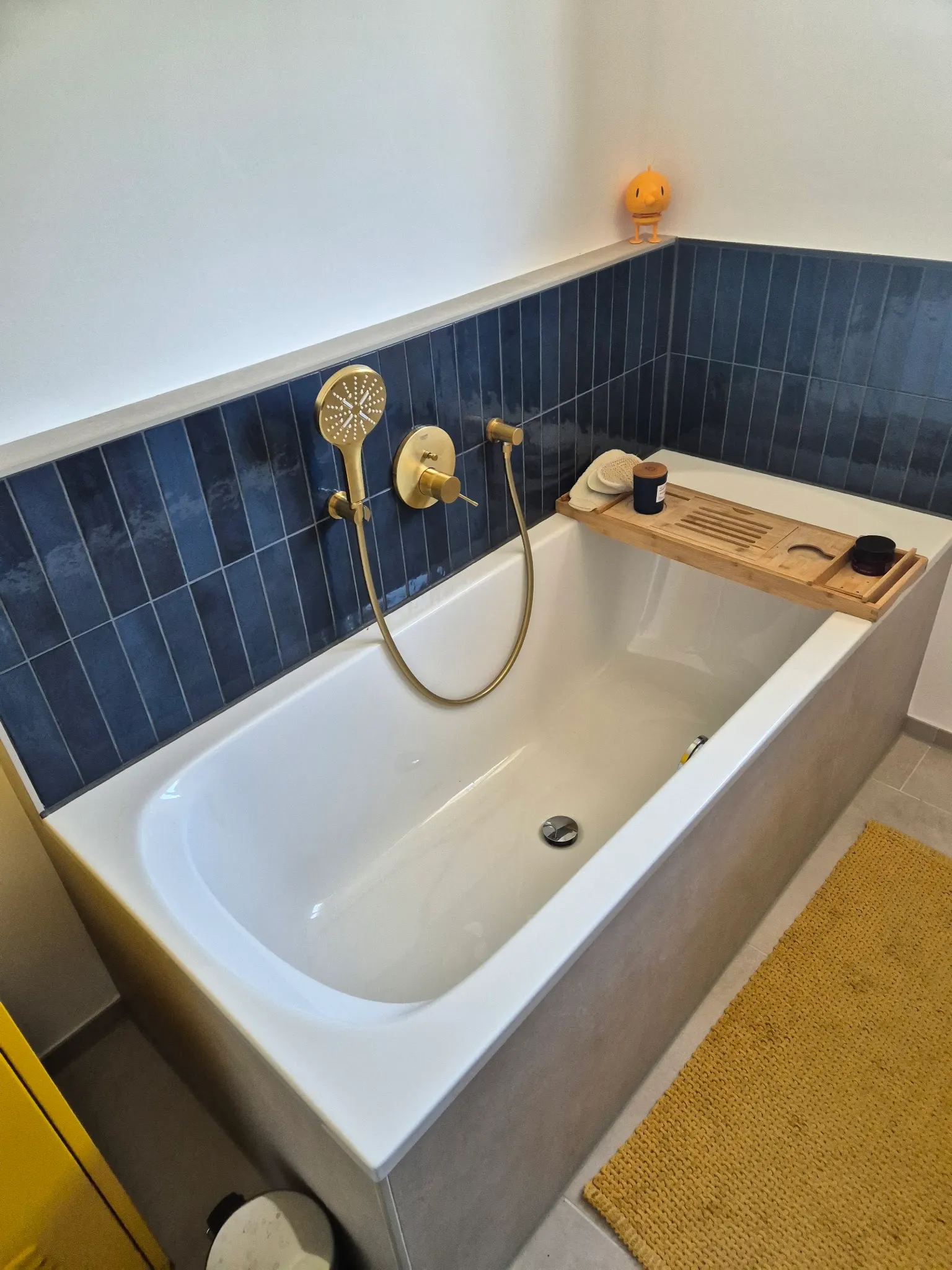 Badewanne mit grauer Verkleidung, Wand mit dunkelblauen Stäbchenfliesen
