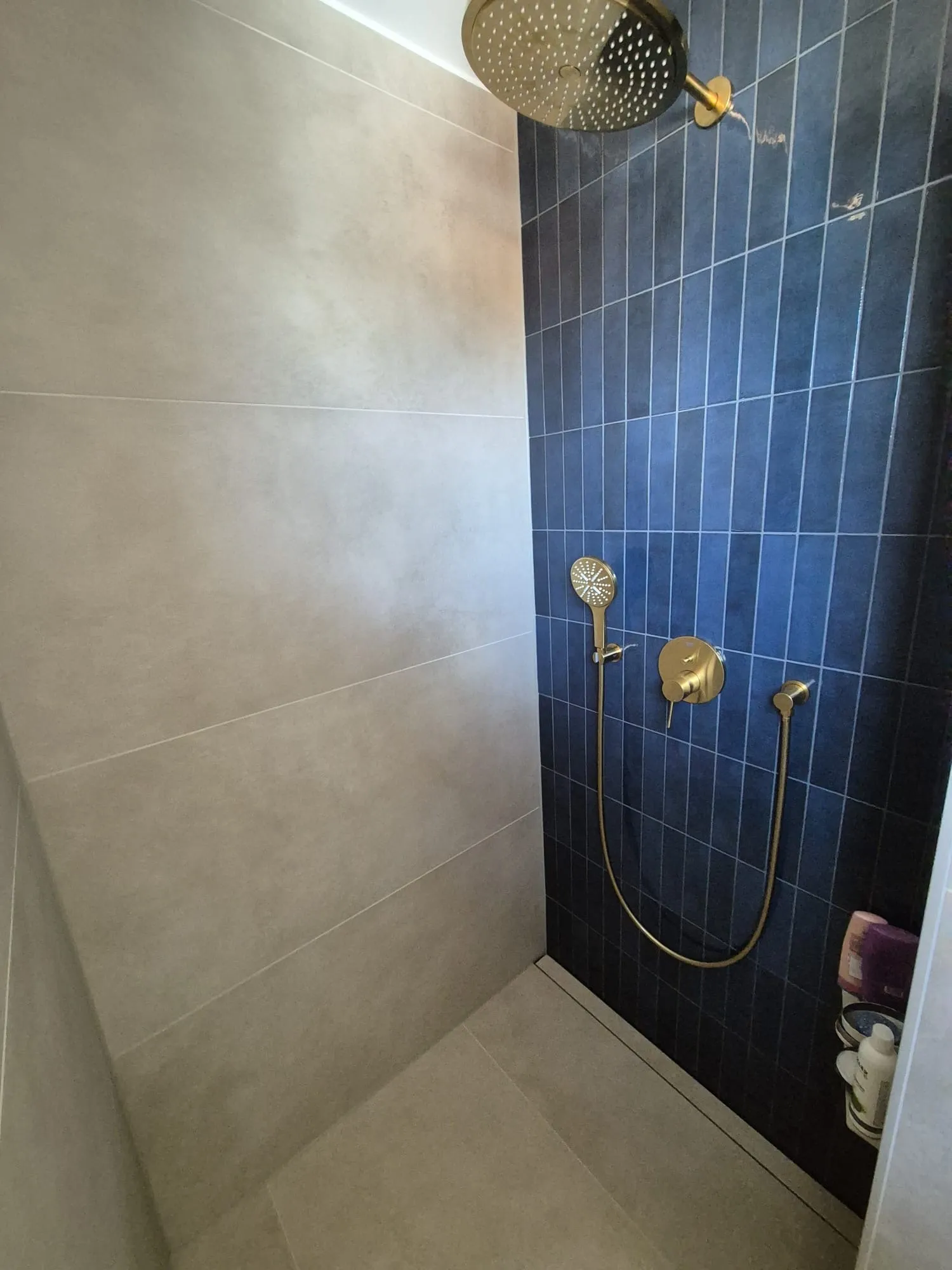 Walk-in-Dusche mit großen grauen Wandplatten und dunkelblauer Akzentwand