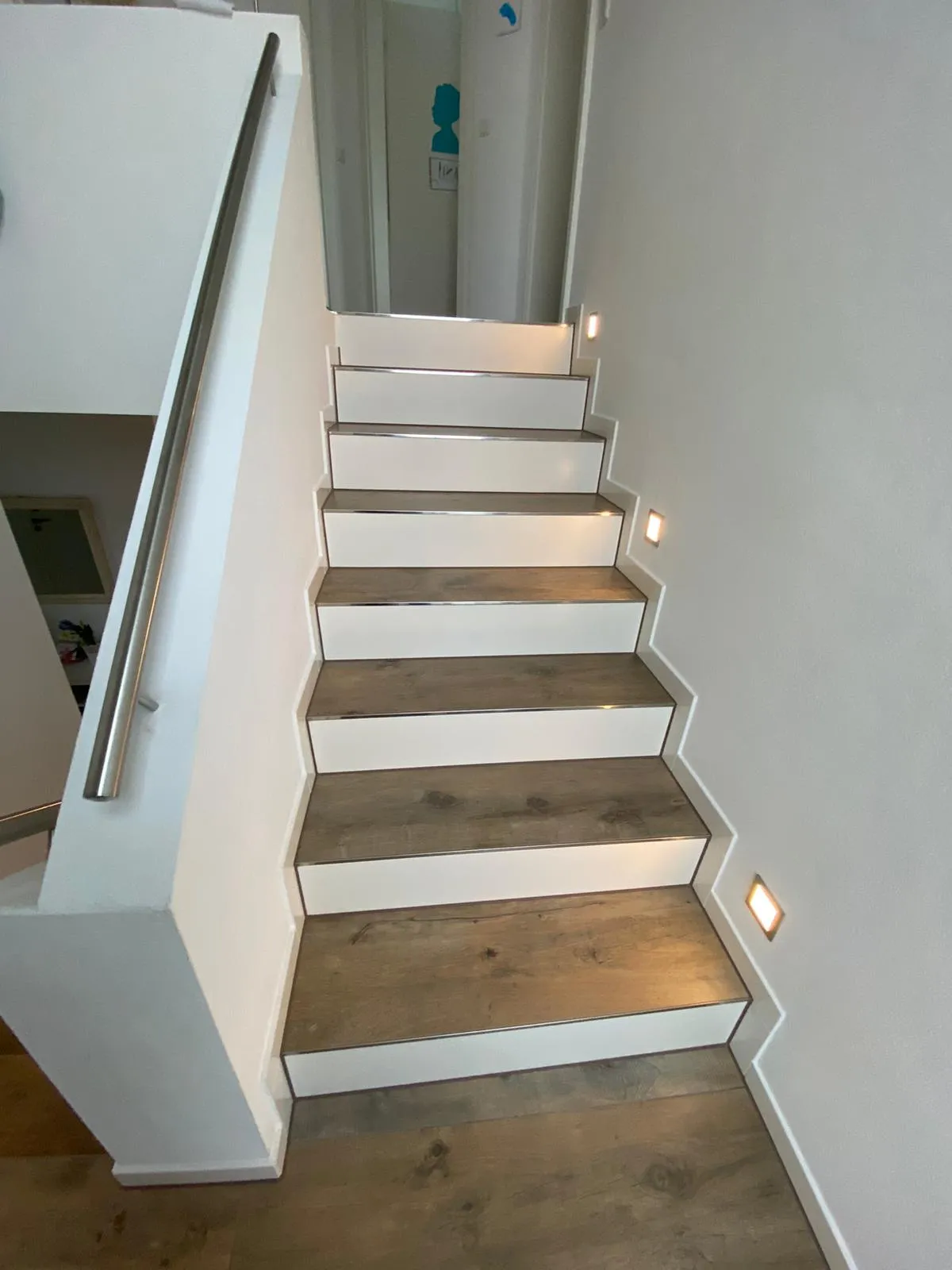 Treppe mit Stufen in Holzoptik und Lichtern in der Wand