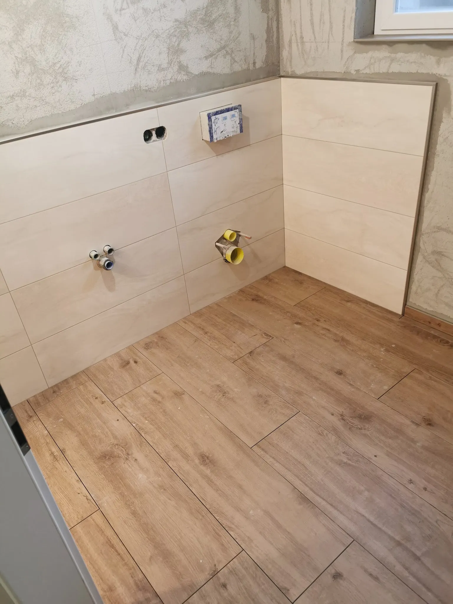 Wohnraum mit Boden in Holzoptik, Wand mit großen hellen Platten
