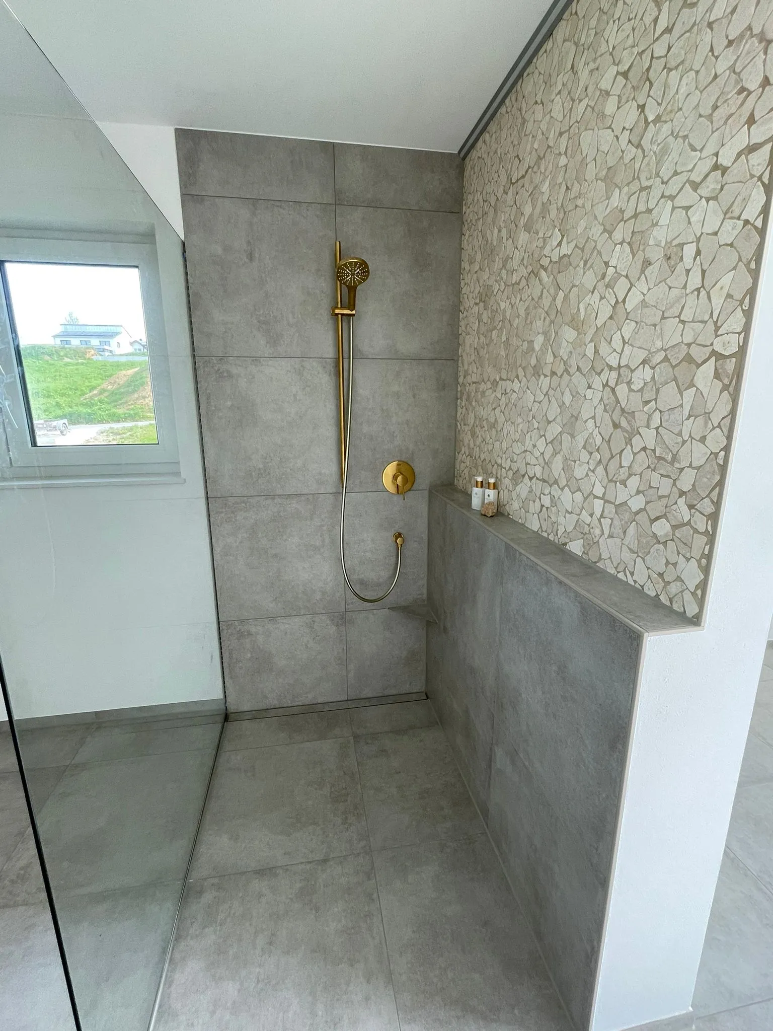 Walk-in-Dusche mit großen grauen Platten und Mosaik-Akzentwand
