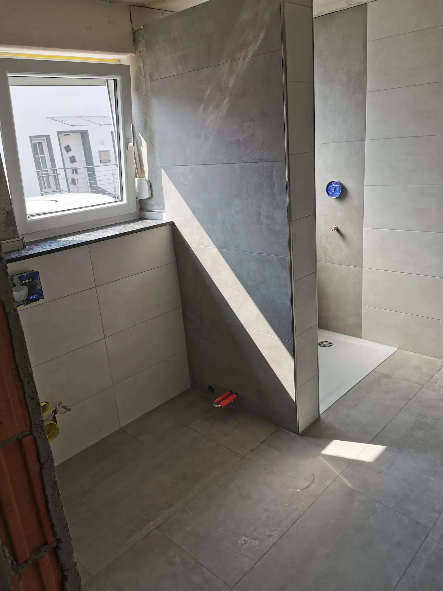 Bad mit großen grauen Wandplatten und bodengleicher Dusche