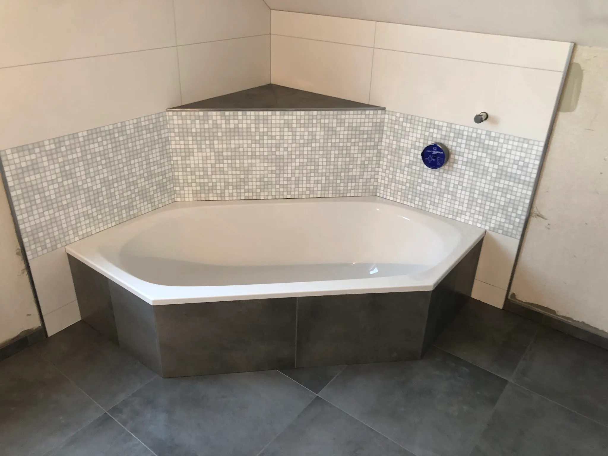 Eckbadewanne mit Mosaik-Bordüre und dunklem Boden