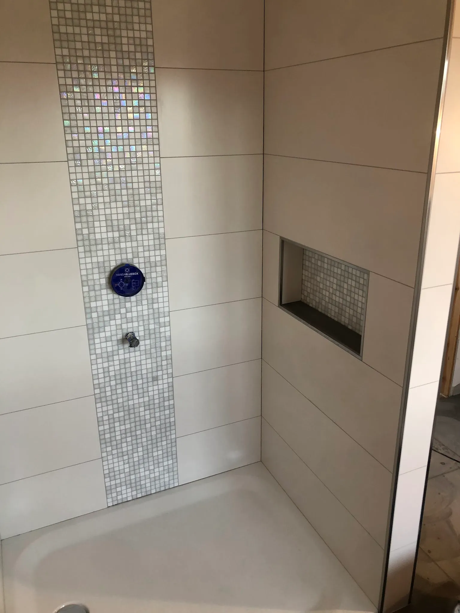 Dusche mit hellen Wandplatten, Mosaik-Streifen und Wandnische