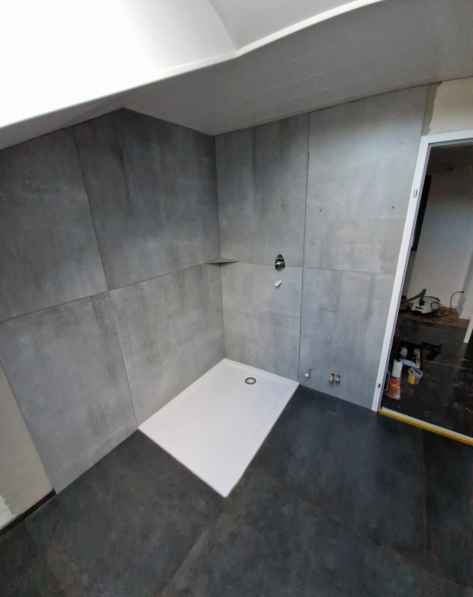 Bad mit großen grauen Wandplatten und dunklem Boden