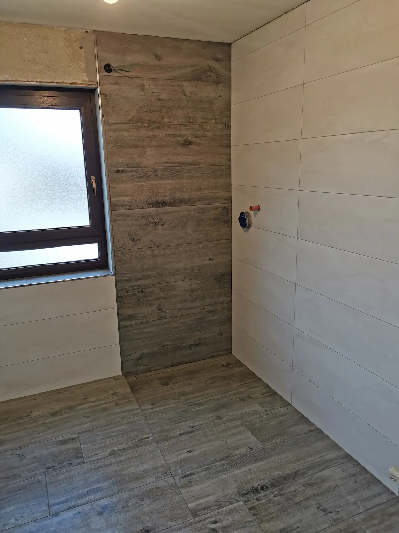 Bad mit Wand in Holzoptik und hellen Platten
