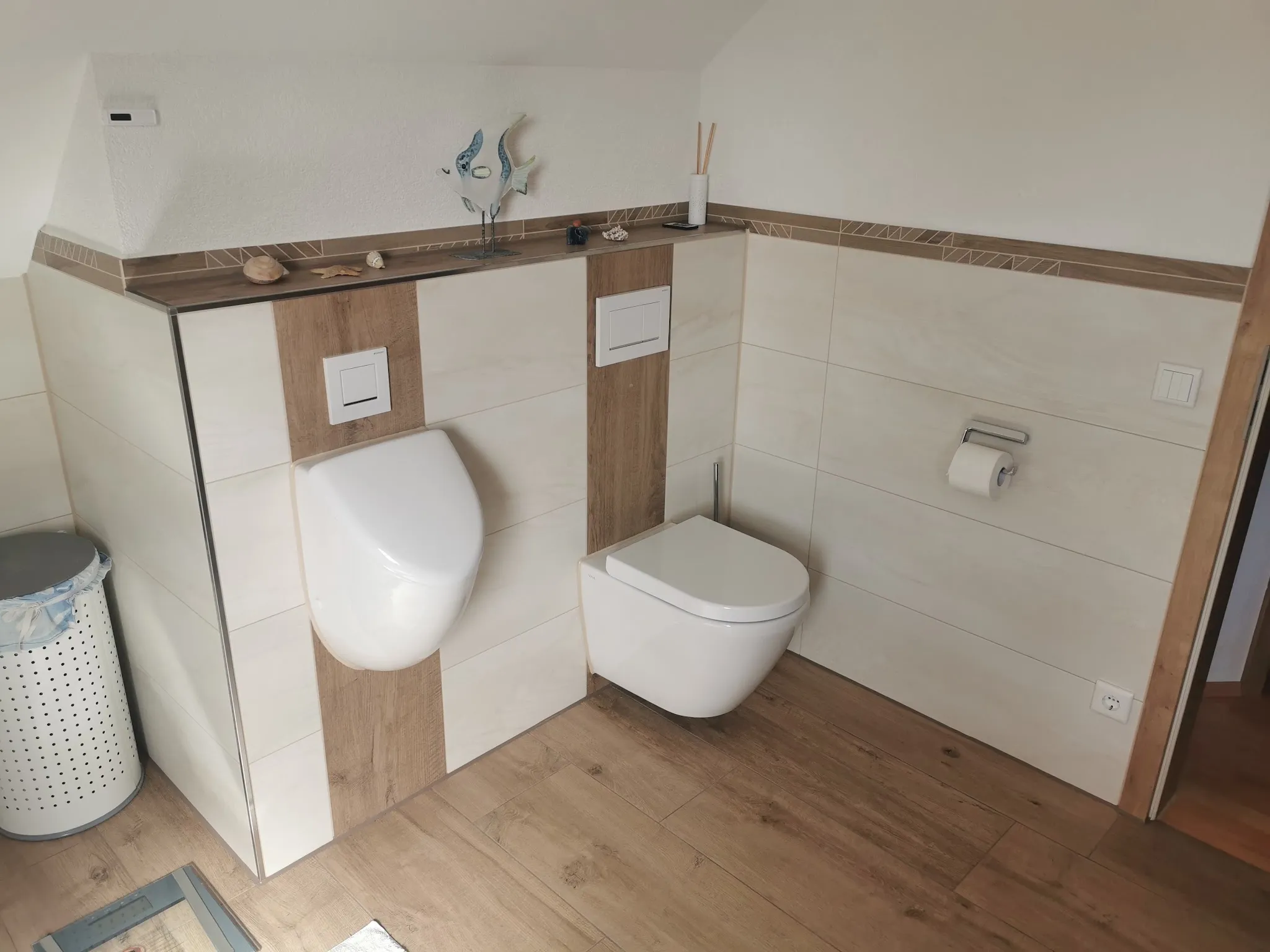 Gäste-WC mit hellen Wandfliesen und Bordüre in Holzoptik