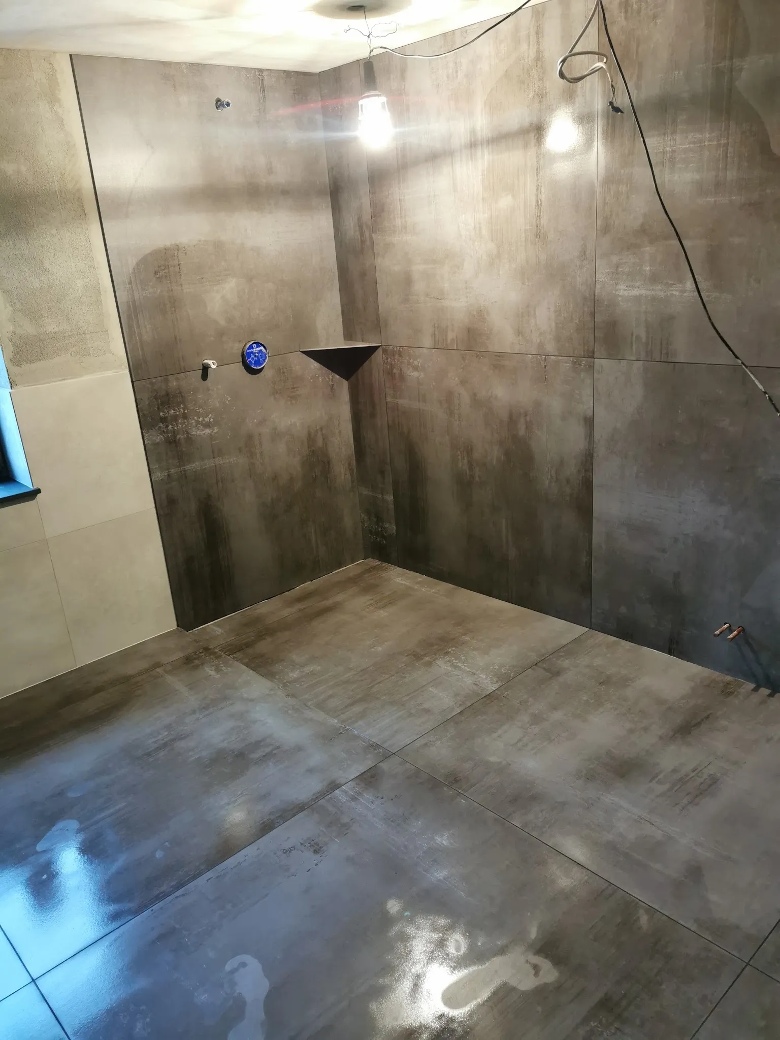 Dusche mit großen dunklen Platten in Beton-Optik