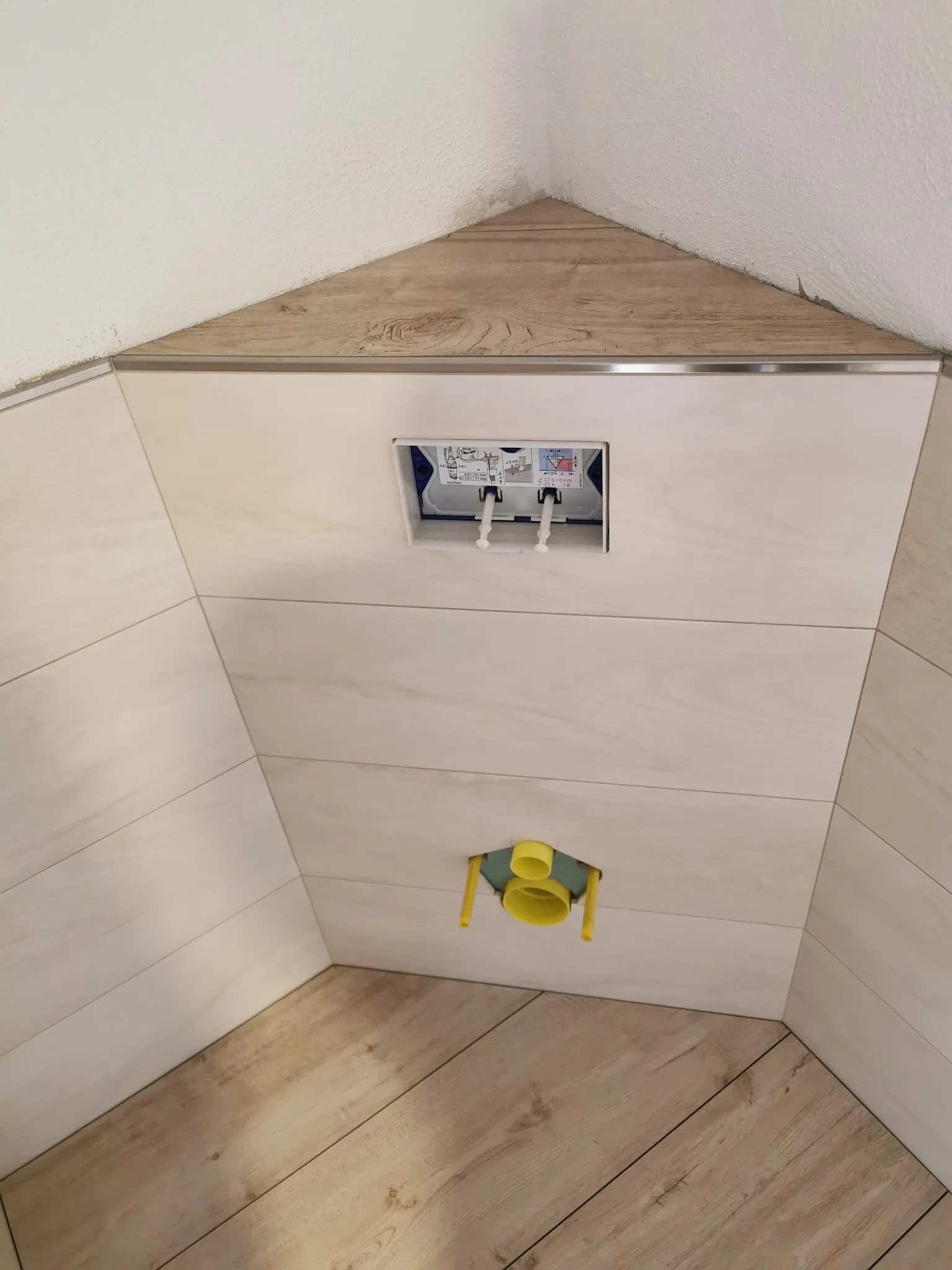 WC-Vorwand mit hellen Fliesen und Abdeckung in Holzoptik