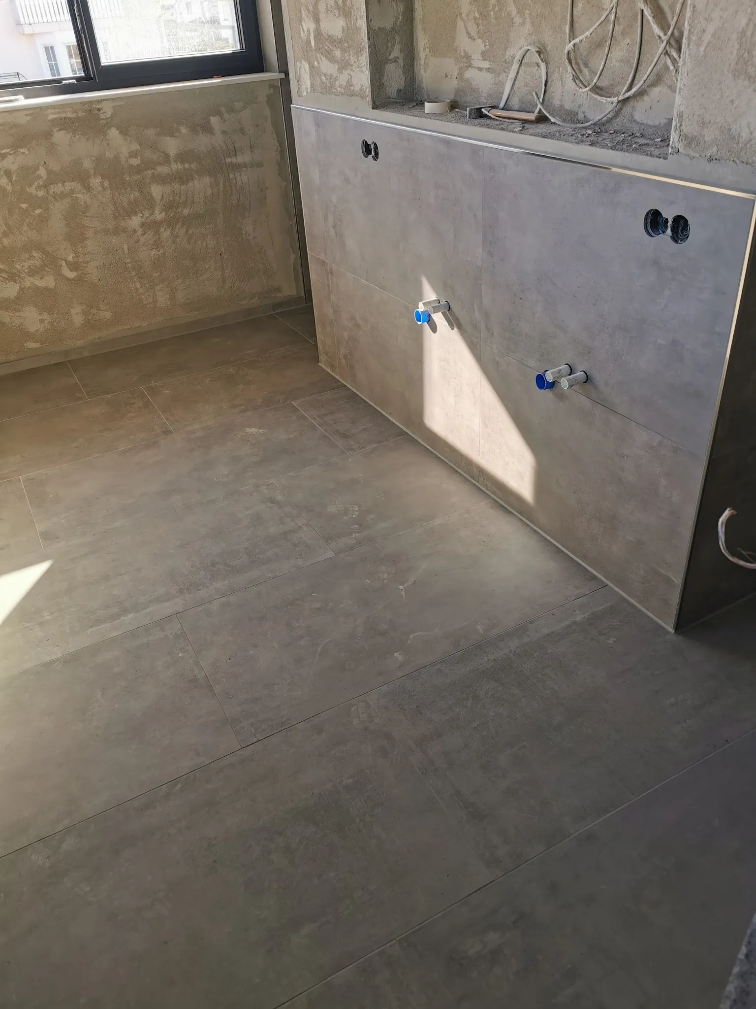 Bad mit großen Platten in Beton-Optik an Wand und Boden