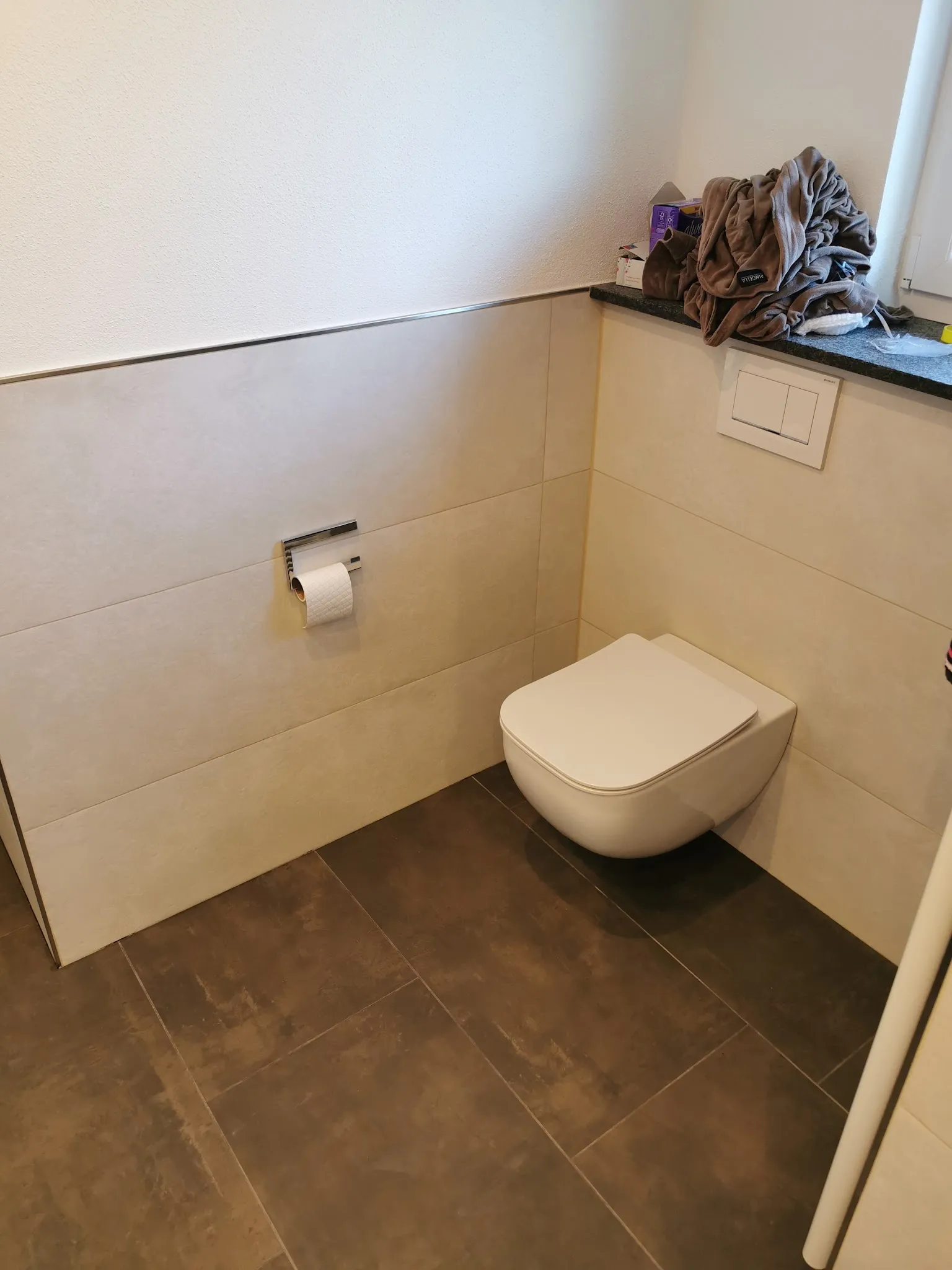 Gäste-WC mit hellen Wandfliesen und dunklem Boden