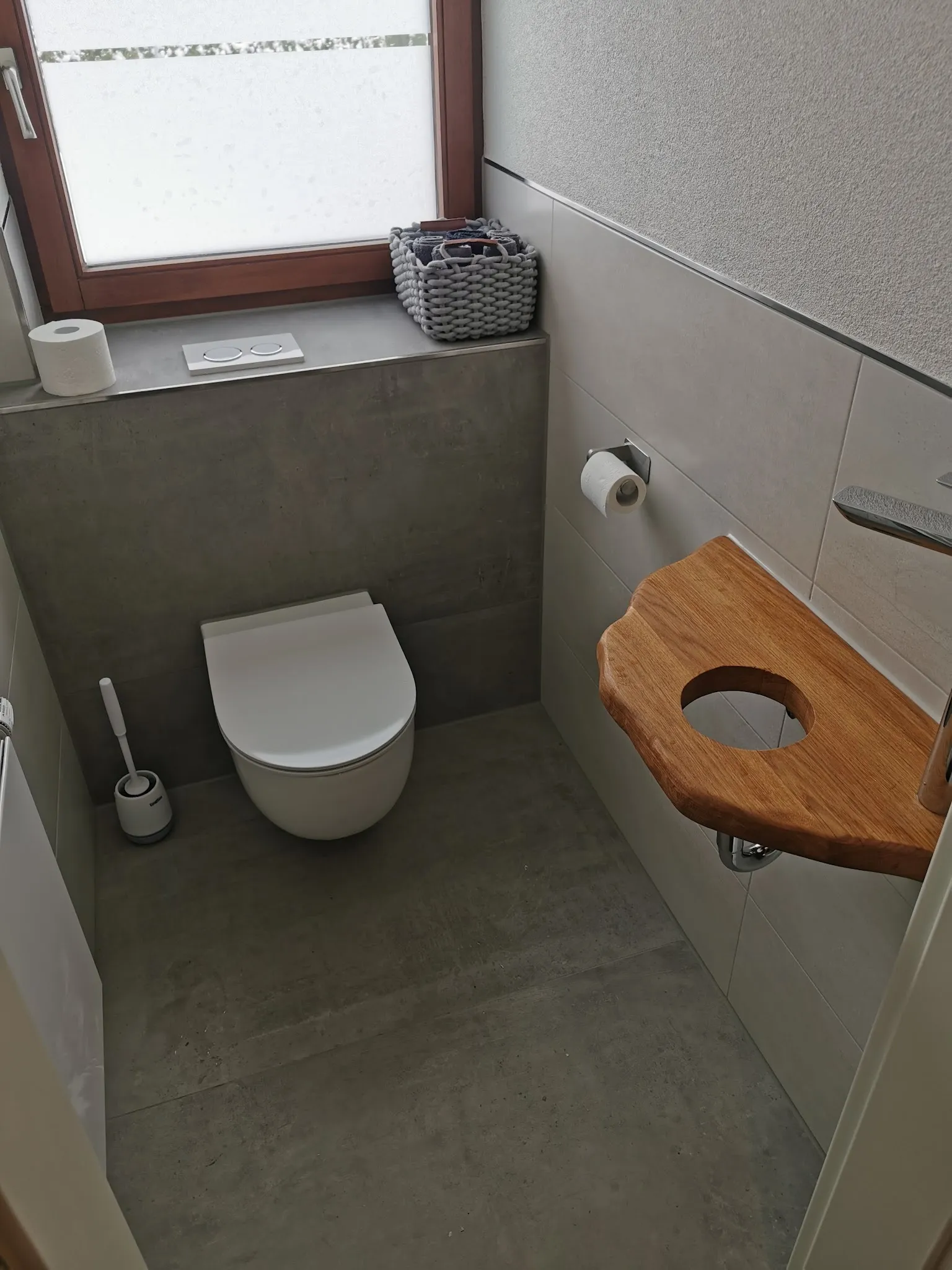 Gäste-WC mit grauen Großformaten und Waschbecken aus Holz